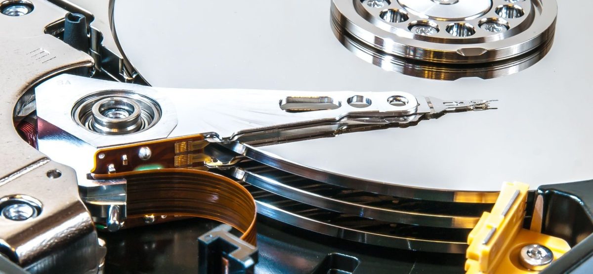 Close-up of an open hard drive showing read/write head, platter, and actuator arm for data recovery